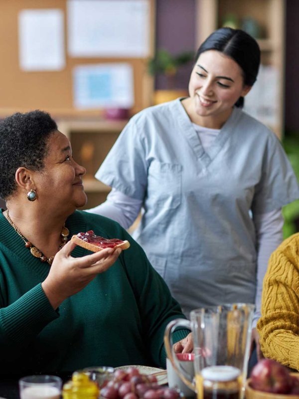 young-nurse-assisting-senior-people-during-breakfa-V26QWH7.jpg